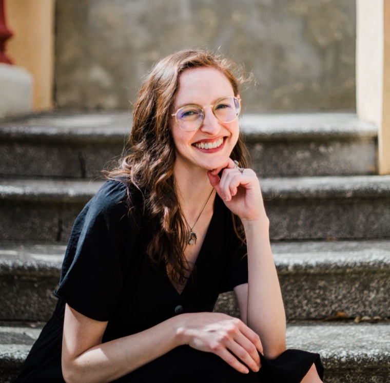 Monica Hay smiling, sitting on stone steps